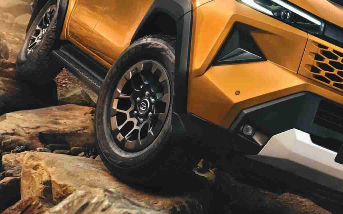 Close-up of the Hilux black alloy wheel and front wheel arch on rocks