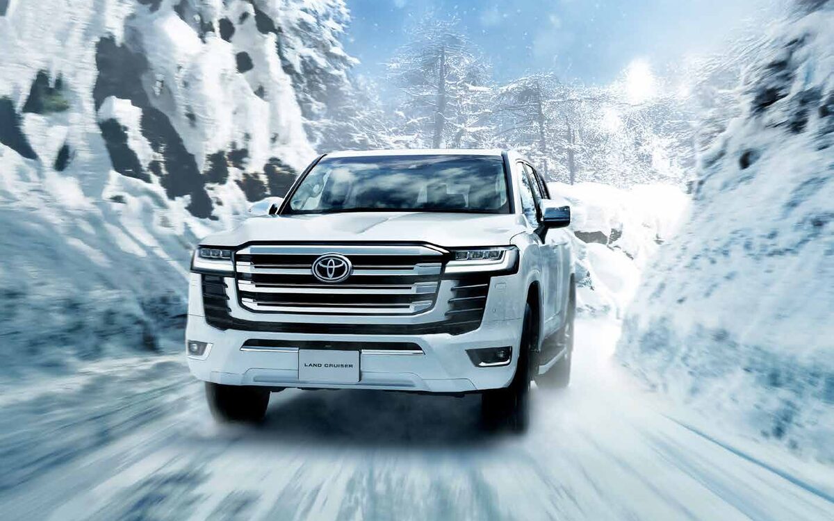 White Toyota Land Cruiser driving towards the camera through a snowy valley