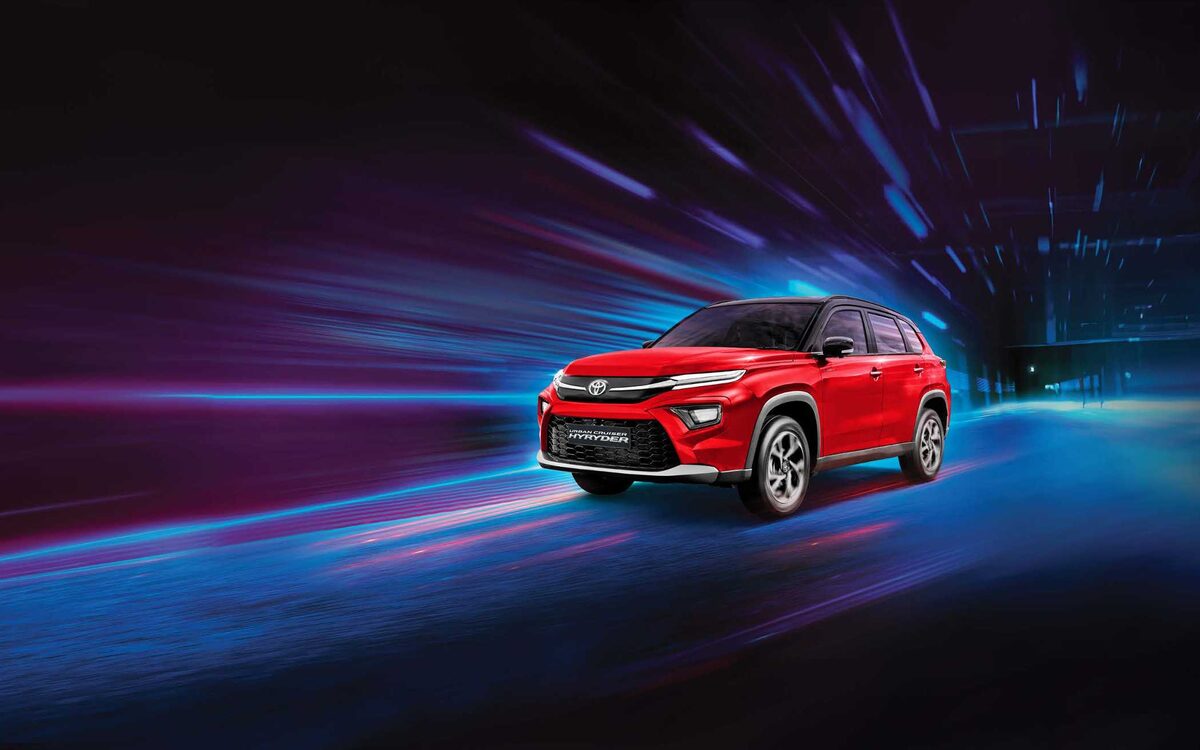 Toyota Urban Cruiser Hyryder in red driving through streaks of blue and purple light