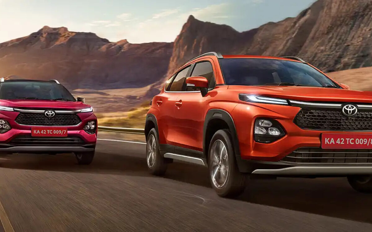 Two Toyota Urban Cruiser Taisors, one orange and one red, driving on a mountain road