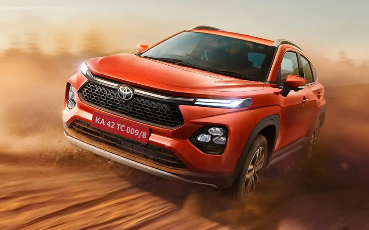 Toyota Urban Cruiser Taisor in orange driving through a cloud of dust