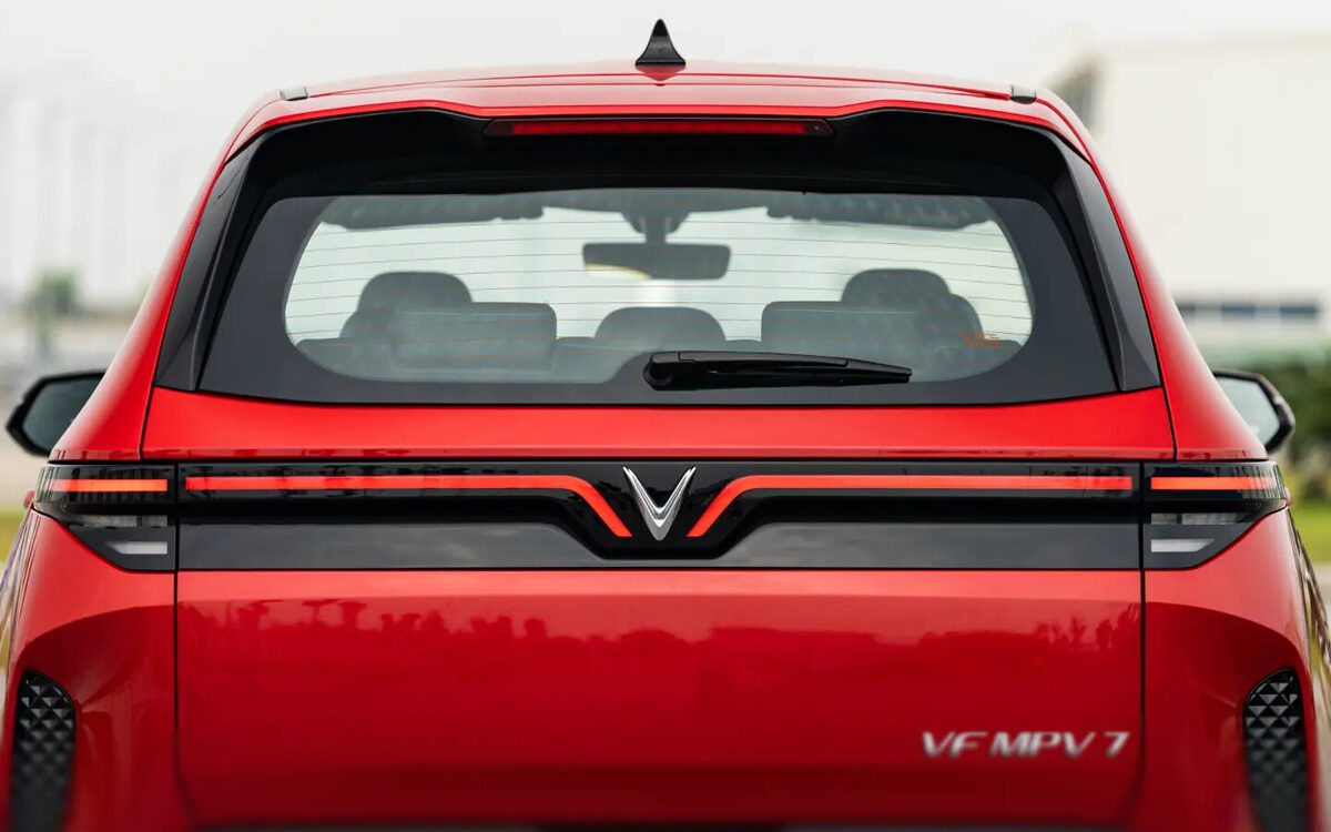 VinFast VF MPV 7 in red, rear view showing the full-width tail lamp bar and V badge