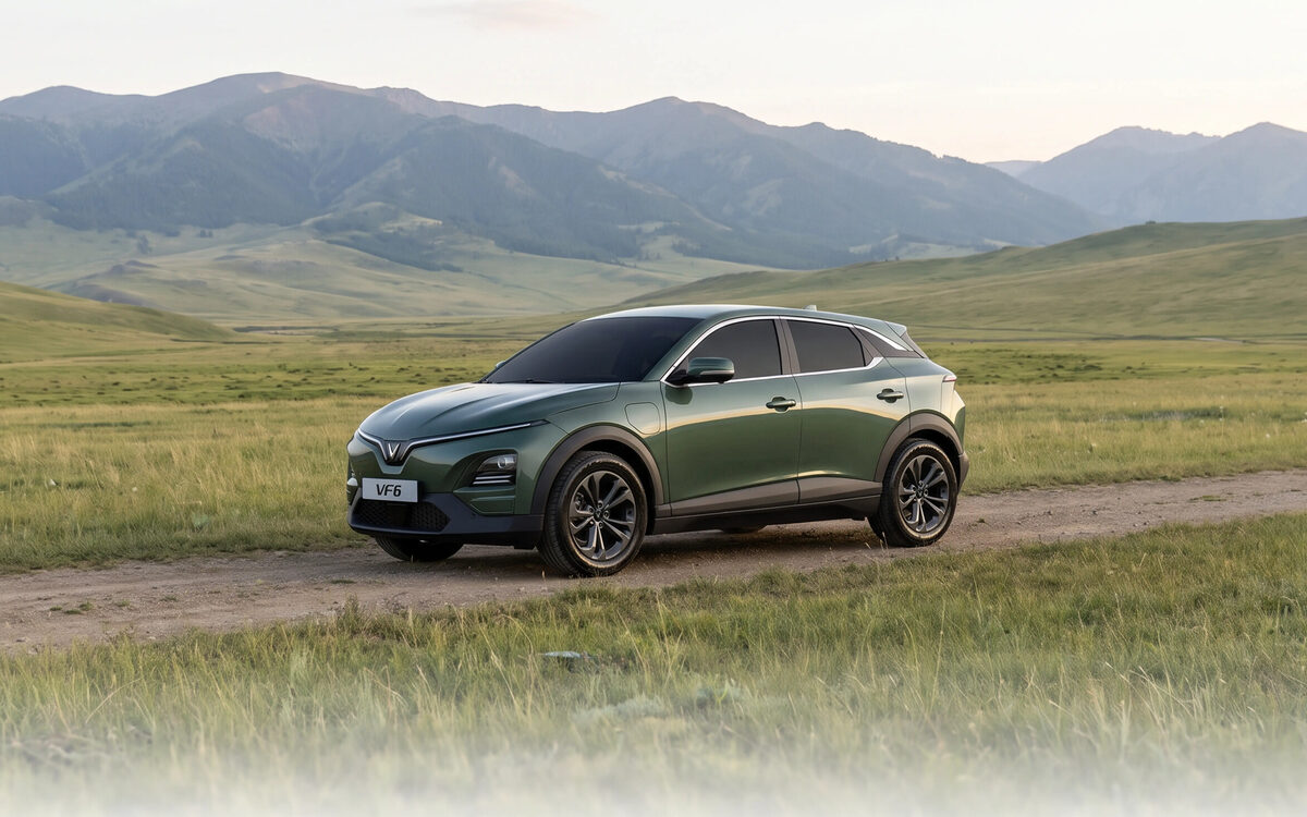 VinFast VF 6 in green driving on a dirt track in a grassland valley