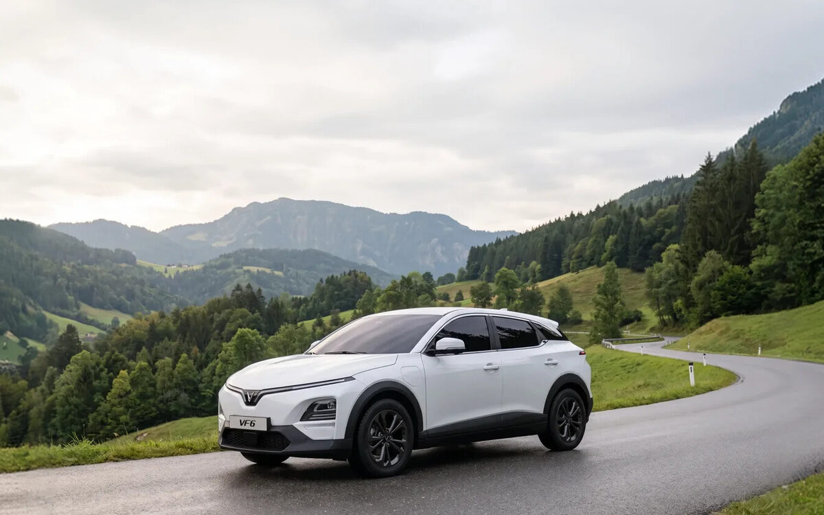 VinFast VF 6 in white on a winding road through green hills