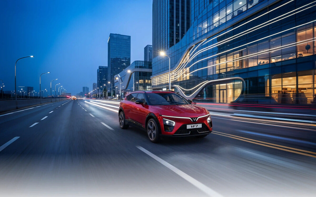 VinFast VF 7 in red driving on a city road at dusk