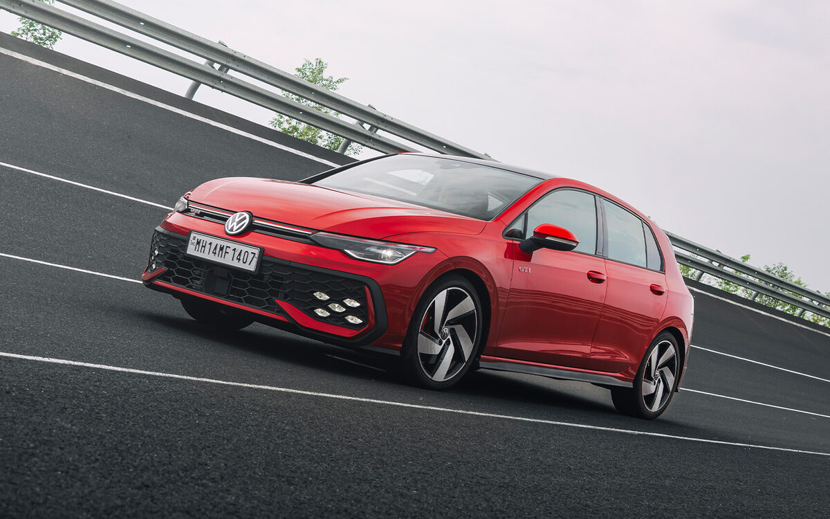 Golf GTI in Kings Red cornering on a test track, front three-quarter view