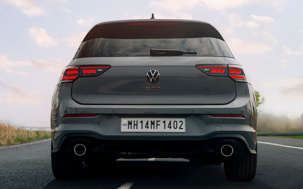 Golf GTI in grey seen from directly behind on an open road, with tail lamps and twin exhausts