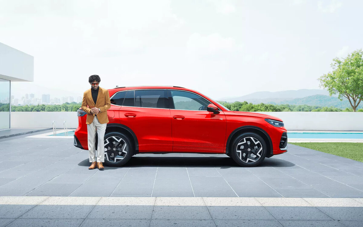 Tiguan R-Line in red, side profile with a man standing beside it