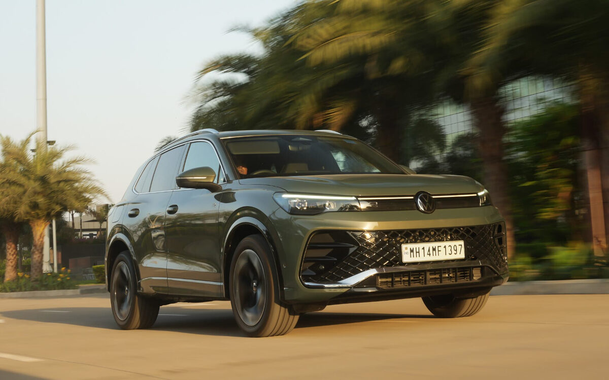 Tiguan R-Line in green driving on a tree-lined road