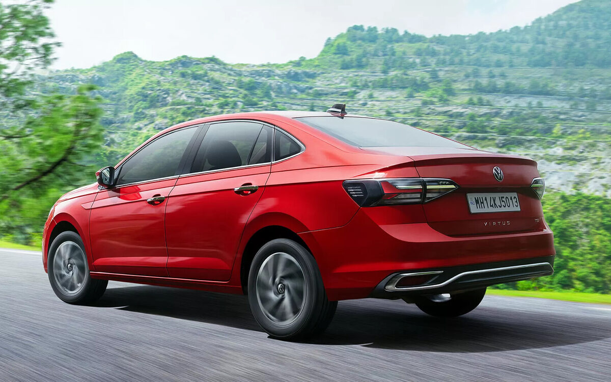Virtus in red, rear three-quarter view driving on a hill road